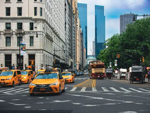 Yellow taxis on a sunny Manhattan avenue lined with tall buildings