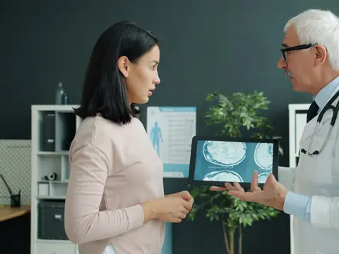 A woman listening as a doctor shows her images on a tablet